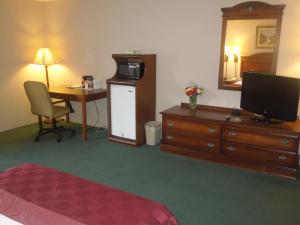 a hotel room with a bedroom with a desk and a television at Pottsville Inn in Pottsville