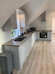 a kitchen with white cabinets and a wooden floor at Peartree Lodge in Cambourne