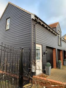 een zwart huis met een hek ervoor bij Peartree Lodge in Cambourne