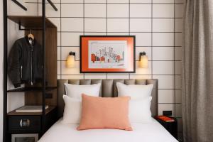 a bedroom with a bed with white pillows and a picture at Hôtel Moderniste in Paris