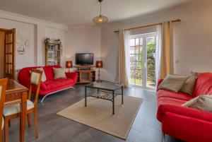un soggiorno con divani rossi e una TV di Villa Casa Branca - with Private Pool & Big Garden a Ribamar