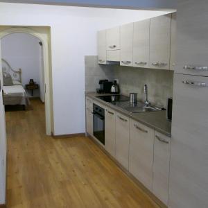 una cucina con armadi bianchi e lavandino di Appartamento Antico Pozzo a Prato