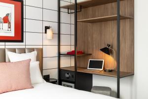 a bedroom with a bed and a laptop on a desk at Hôtel Moderniste in Paris