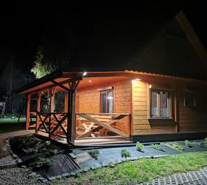 a small wooden cabin with a porch at night at DOMEK LENA ROZTOCZE in Hutki