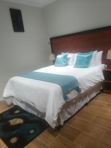 a bedroom with a large bed with blue pillows at LALA POA GUEST HOUSE in Klerksdorp