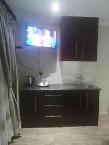 a kitchen with a flat screen tv on the wall at LALA POA GUEST HOUSE in Klerksdorp