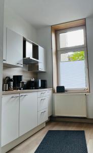 una cucina con armadi bianchi e una grande finestra di FeWo Alte Bäckerei a Dessau