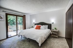 a bedroom with a bed with white sheets and orange pillows at Geyser Getaway in West Yellowstone