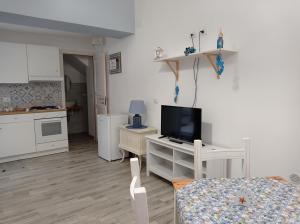 a living room with a tv and a kitchen at Mare Dentro - Heart of Siracusa in Siracusa