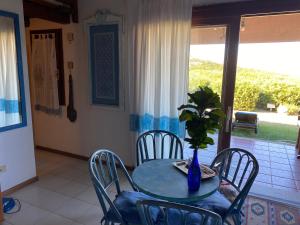 圣特奥多罗villino D5 coda cavallo villaggio cala paradiso的桌子,椅子,花瓶,上面有植物 更多30张照片