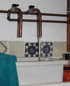 a sink with two faucets and a blue and white tiles at The Old Apple Shed cosy heated cottage in a meadow close to the charming village of Bethersden in Ashford