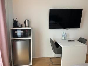 a room with a white desk with a tv on a wall at HAUS 7 - Boardinghouse in Kornwestheim
