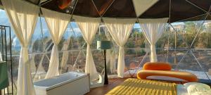 a room with a tub and a chair in front of a window at Glamping Skies - Adults Only in Estremoz