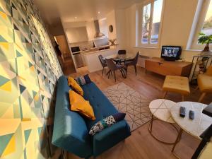 uma sala de estar com um sofá azul e uma cozinha em Appart 2 Cosy Annœullin - Proche toutes commodités em Annoeullin