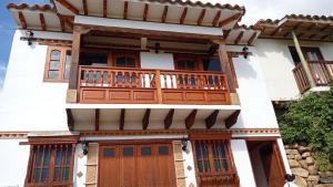 una casa con porte in legno e balcone di Casa Hotel La Villa del Rosario a Villa de Leyva