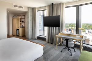 een hotelkamer met een bed, een bureau en ramen bij Jasper Hotel in Fargo