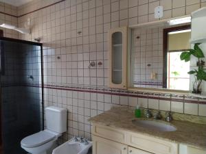 a bathroom with a toilet and a sink and a mirror at Casa 5 suítes com piscina e churrasqueira in Ubatuba +27 photos