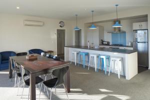 a kitchen with a table and some blue stools at Blae Loch - Lake Tekapo in Lake Tekapo