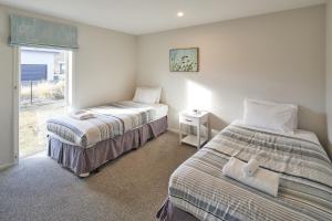 two beds in a room with a window at Blae Loch - Lake Tekapo in Lake Tekapo