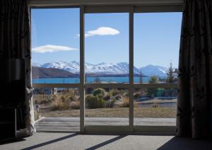 an open window with a view of snow covered mountains at Blae Loch - Lake Tekapo in Lake Tekapo