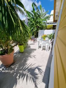 a patio with a table and chairs and palm trees at Ti Pècheur in Sainte-Luce