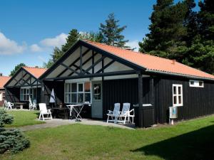 a black cottage with white chairs in a yard at Holiday home Væggerløse CVIII in Marielyst