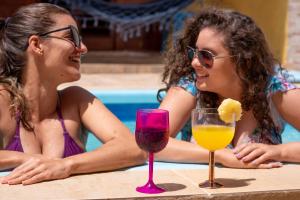 duas mulheres sentadas numa mesa com bebidas numa piscina em Toca do hamster - MILAGRES em São Miguel dos Milagres