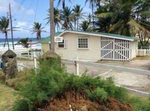 a small white house on the beach with palm trees at Rest Haven Beach Cottages in Saint Joseph