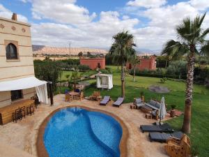 a swimming pool in a yard with tables and chairs at Villa Diaf Johanne in Aït Ourir
