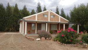 a brick house with pink flowers in front of it at Quinta El Descanso in Puerto Madryn