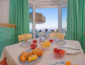 einen Tisch mit Gebäck und Obst in Schalen darauf in der Unterkunft Hotel Casa del Sole in Ischia