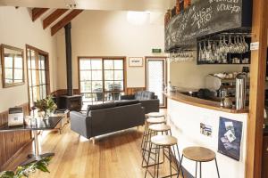 a bar in a restaurant with a couch and stools at Little Norfolk Bay Events and Chalets in Taranna