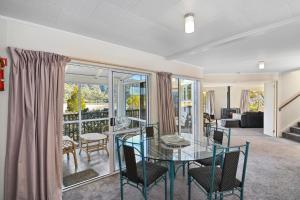 a living room with a glass table and chairs at Millard House - Marlborough Sounds in Grove