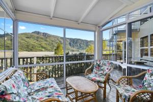 a screened porch with chairs and a table and windows at Millard House - Marlborough Sounds in Grove