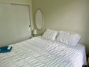 a bedroom with a white bed with a mirror at Jennie's In Whitianga in Whitianga