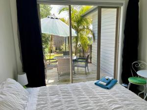 a bedroom with a bed and a patio with an umbrella at Jennie's In Whitianga in Whitianga