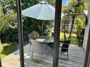 a table and chairs with an umbrella on a deck at Jennie's In Whitianga in Whitianga +16 photos