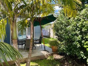 a wooden deck with a table and chairs and an umbrella at Jennie's In Whitianga in Whitianga