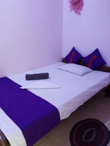 a bedroom with a large bed with purple and white sheets at Evening Star Guest Inn in Kandy