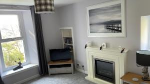 a living room with a fireplace and a television at Beautiful cottage in a wonderful Highland setting in Drumbeg