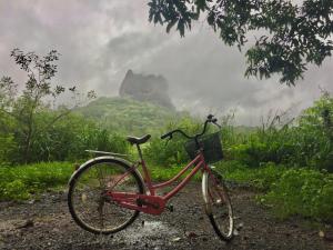 a red bike parked on a path with a mountain in the background at Sigiri Shen Residence in Sigiriya
