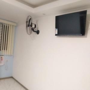 a flat screen tv on a white wall with a fan at Hotel Gold Park in Franco da Rocha