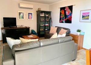 a living room with a couch and a television at Wintersun Holiday Cottages in Emu Bay