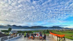 un gruppo di persone seduti ai tavoli su un balcone di Depik Inn a Takengon