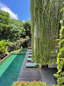 a swimming pool with a bunch of chairs next to it at ARTOTEL Haniman Ubud in Ubud