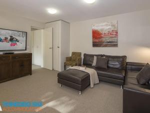 a living room with a leather couch and a tv at Golden Eagle 1 in Thredbo