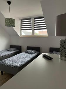 Habitación con 2 camas, mesa y ventana en Hanuszówka pokoje gościnne z łazienkami, en Nysa