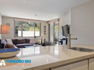 a kitchen with a sink and a living room at Squatters Run 14 in Thredbo