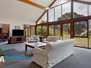 a living room with white furniture and large windows at The Little Nap in Crackenback