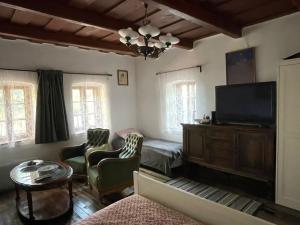 a living room with a television and a couch and chairs at Róza Vendégház in Buják